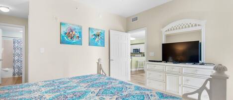 A bedroom with a bed, a TV, and artwork on the wall.