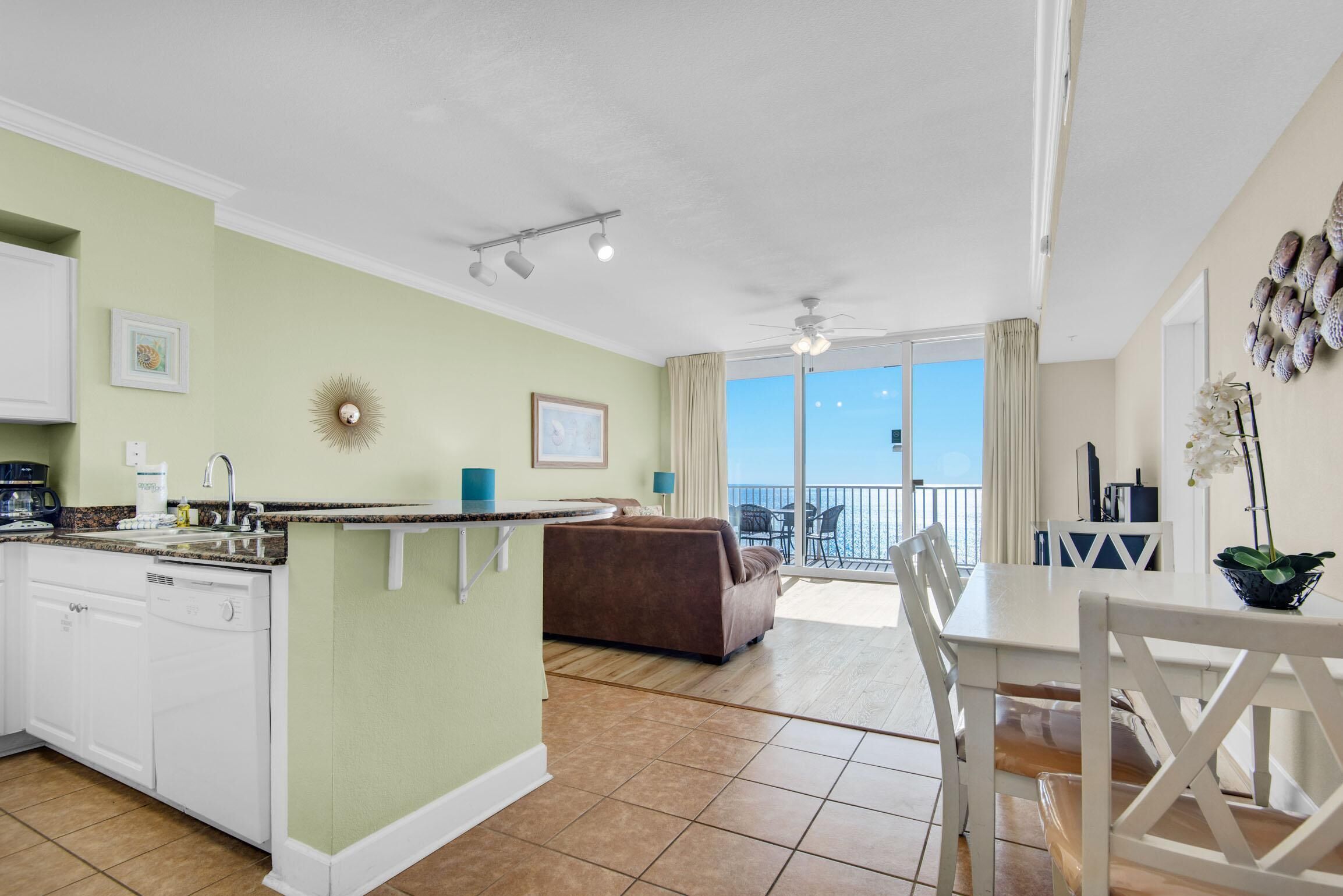 A spacious living area with a kitchen, dining table, and a balcony with a view.