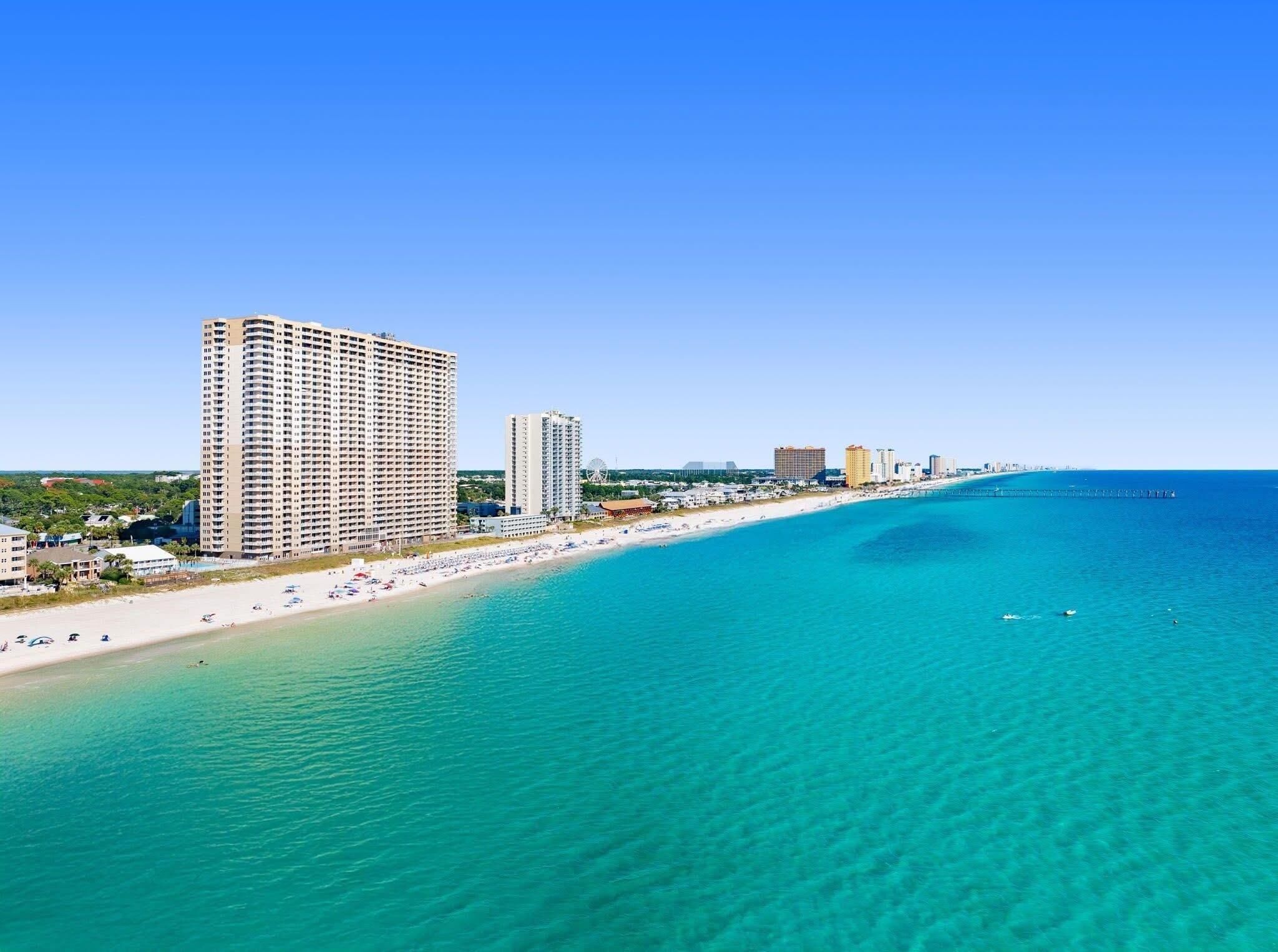 Un paisaje urbano costero con playa, rascacielos y cielo azul despejado.