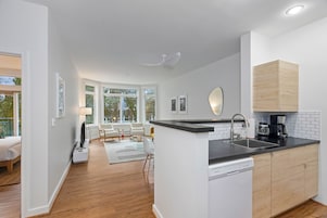 Una cucina moderna con piano di lavoro nero, mobili bianchi e lavastoviglie integrata.