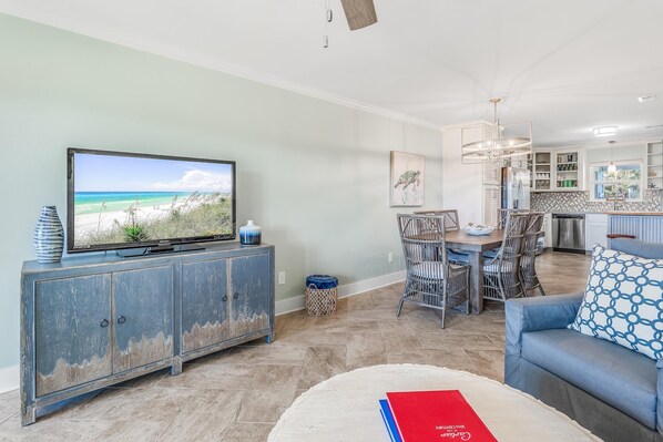 A living room with a television, a dining area, and a kitchen.