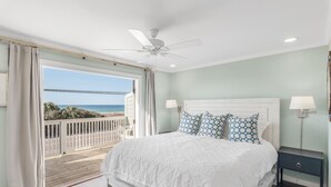Ein Schlafzimmer mit einem großen Bett, einem Deckenventilator und Blick aufs Meer.