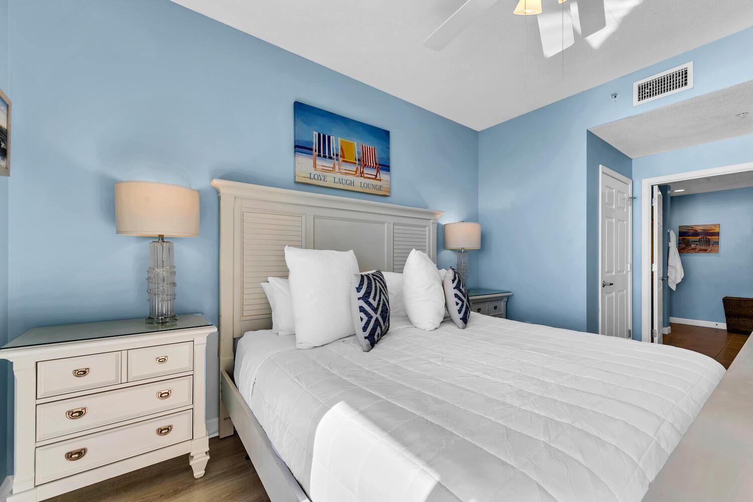 A bedroom with a bed, nightstands, and a painting on the wall.
