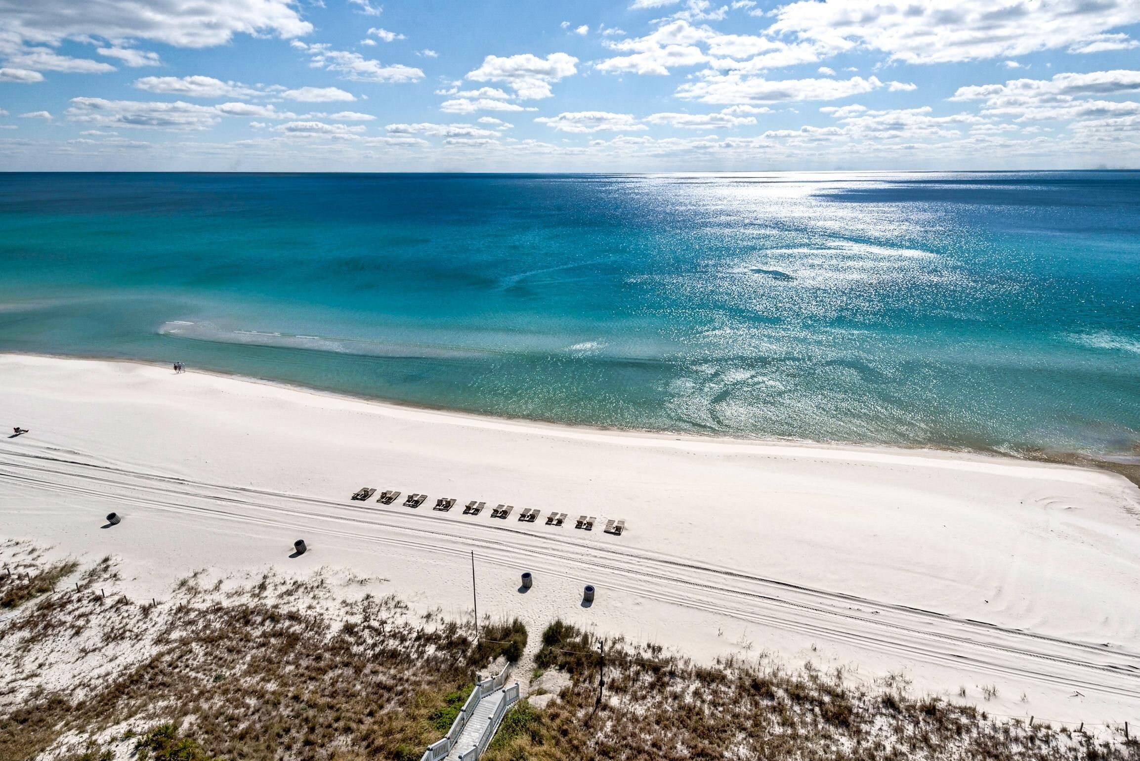 Una spiaggia con cielo sereno, mare calmo e una battigia sabbiosa.