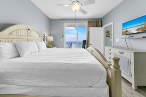 A hotel room with a large bed, a ceiling fan, a TV, and a view of the ocean. - Splash 1802e (Panama City Beach)