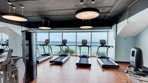 A gym with treadmills, a rowing machine, and a stationary bike, overlooking a beach. - Splash 1102e (Panama City Beach)
