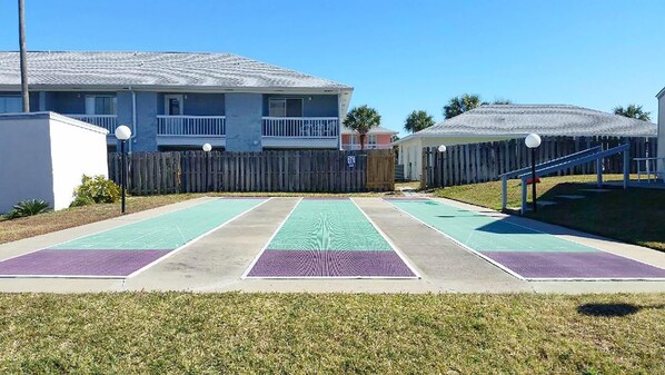 A residential area with a tennis court, a wooden fence, and a building with a balcony. - Southwind I-9 (Panama City Beach)