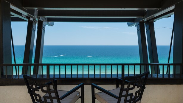 A balcony with two chairs facing a view of the ocean. - Origin at Seahaven 825 (Panama City Beach)