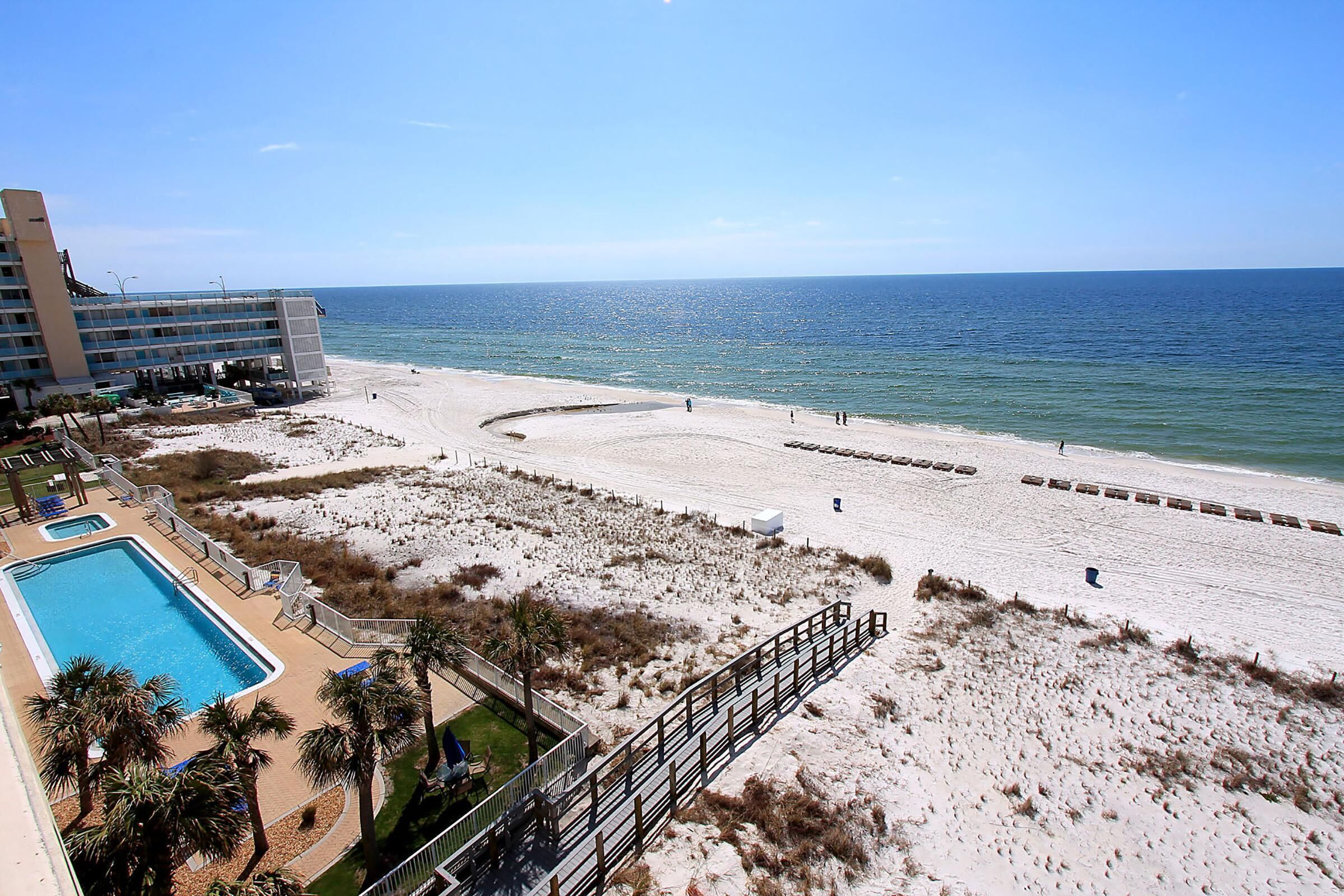 A beach resort with a swimming pool, beach access, and a view of the ocean.