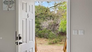 A white door with a view of a natural landscape through a window. - 8 acres Ranch - 3 Homes - Sleeps 24 - Dripping (Dripping Springs)