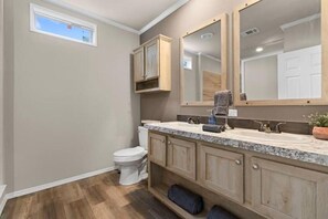 Une salle de bain équipée de toilettes, d’un lavabo, d’un miroir et de meubles en bois.