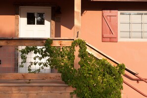 A wooden staircase with a metal railing, a white door, and a window with a shutter. - The Valley House, Unit 1 (Sierraville)