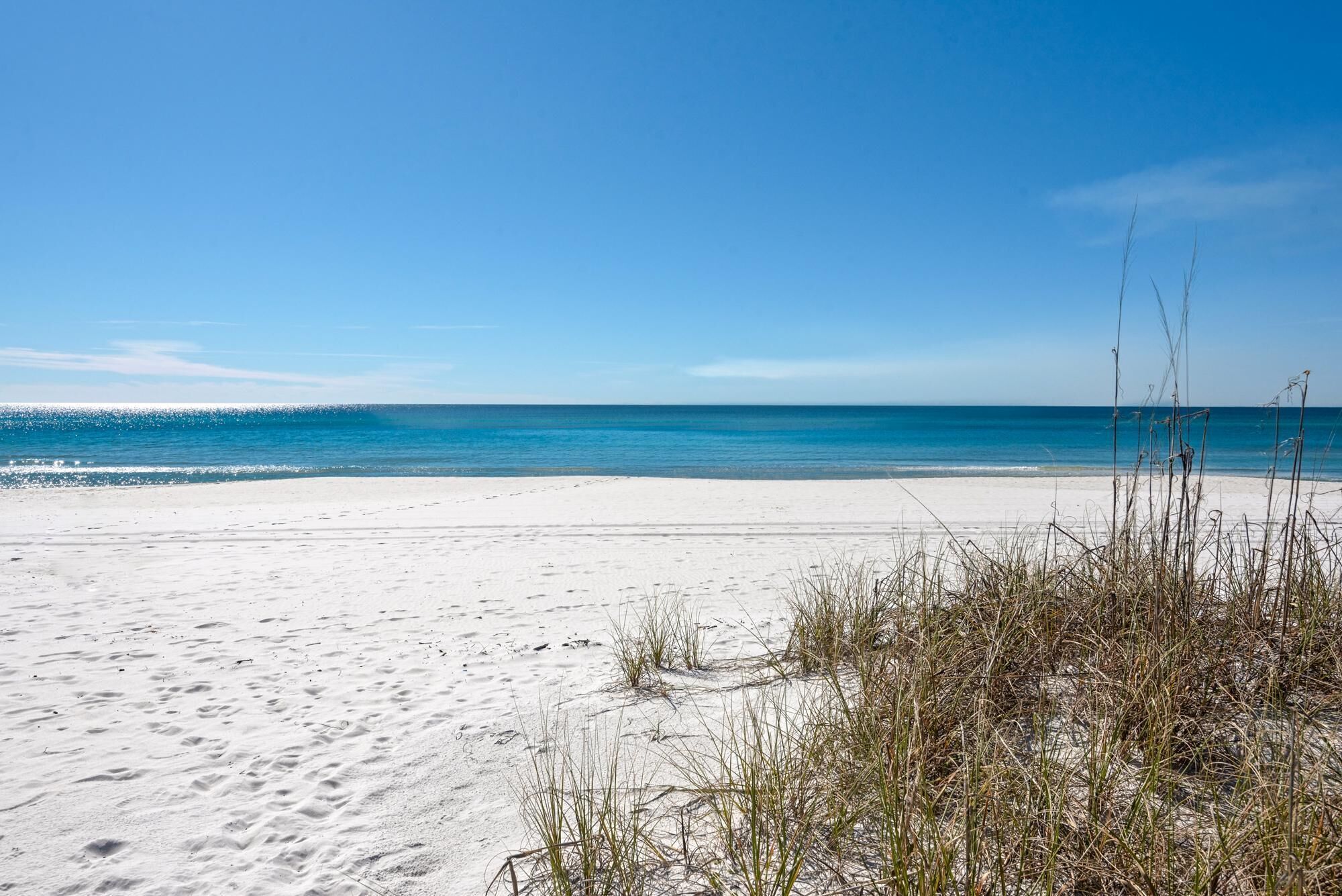 Ein Strand mit weißem Sand und klarem, blauem Wasser.