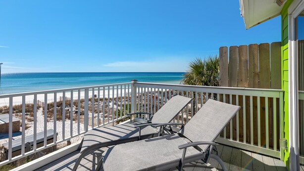 Een balkon met twee loungestoelen gericht op het strand.