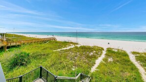 Ein Strand mit einer Holzpromenade, die zu einem Sandstrand und einer Rasenfläche führt.