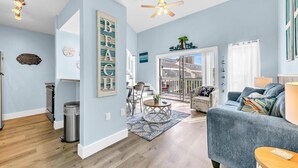 A spacious living room with a blue sofa, a coffee table, and a ceiling fan. - Endless Summer F11 (Panama City Beach)