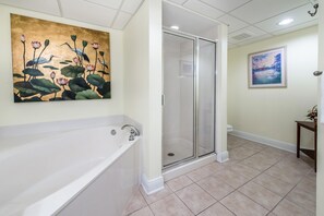Relax in a serene space with a large bathtub and glass-enclosed shower area.