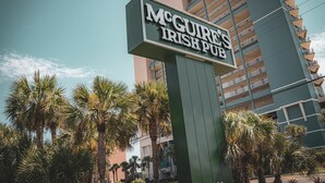 A sign for McGure's Irish Pub with a modern building in the background. - Emerald Beach 1627 (Panama City Beach)