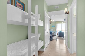 A hallway with bunk beds, a dining area, and a bathroom. - Celadon 703 (Panama City Beach)