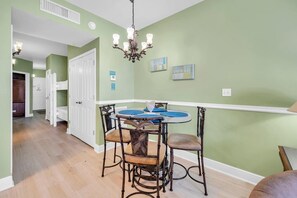 A dining area with a round table, chairs, and a chandelier. - Celadon 703 (Panama City Beach)