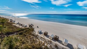 Une plage avec une clôture en bois, des chaises de plage et des parasols.