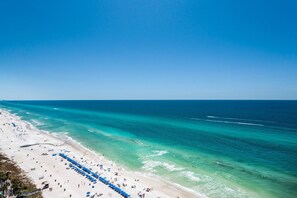 A beach with a row of blue umbrellas and a sandy shoreline. - Celadon 1902 "aloha No Ka Oi" (Panama City Beach)