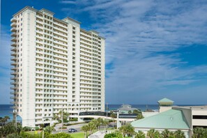 A tall, multi-story hotel with a central courtyard and a view of the ocean. - Celadon 1902 "aloha No Ka Oi" (Panama City Beach)