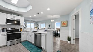 Una cocina moderna con armarios blancos, electrodomésticos de acero inoxidable y una isla central.