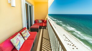 A balcony with red cushioned seating and a view of the ocean. - Calypso 2-2304 West (Panama City Beach)