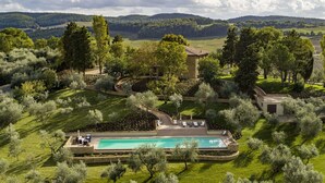 A large, private property with a swimming pool, lush greenery, and a stone building.