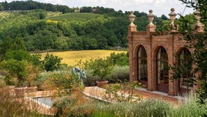 A brick building with arched windows and a garden with a pond.