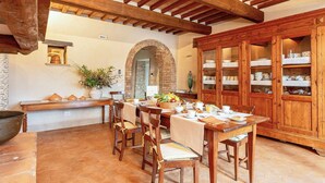 A rustic dining area with wooden furniture, a brick wall, and a wooden cabinet with dishes.