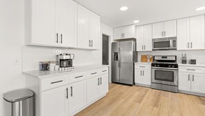 A modern kitchen with white cabinets, stainless steel appliances, and a wooden floor. - Casa Blanca  (Kyle)