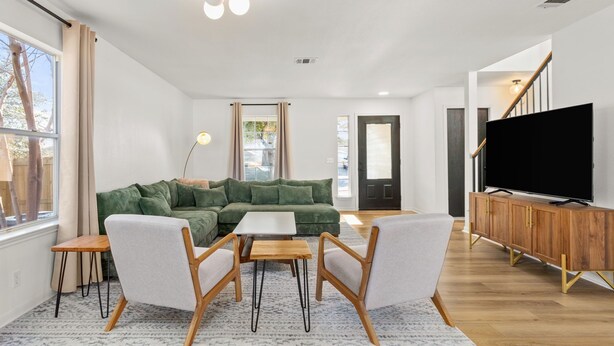 A modern living room with a green sofa, two armchairs, a coffee table, a TV, and a wooden cabinet. - Casa Blanca  (Kyle)