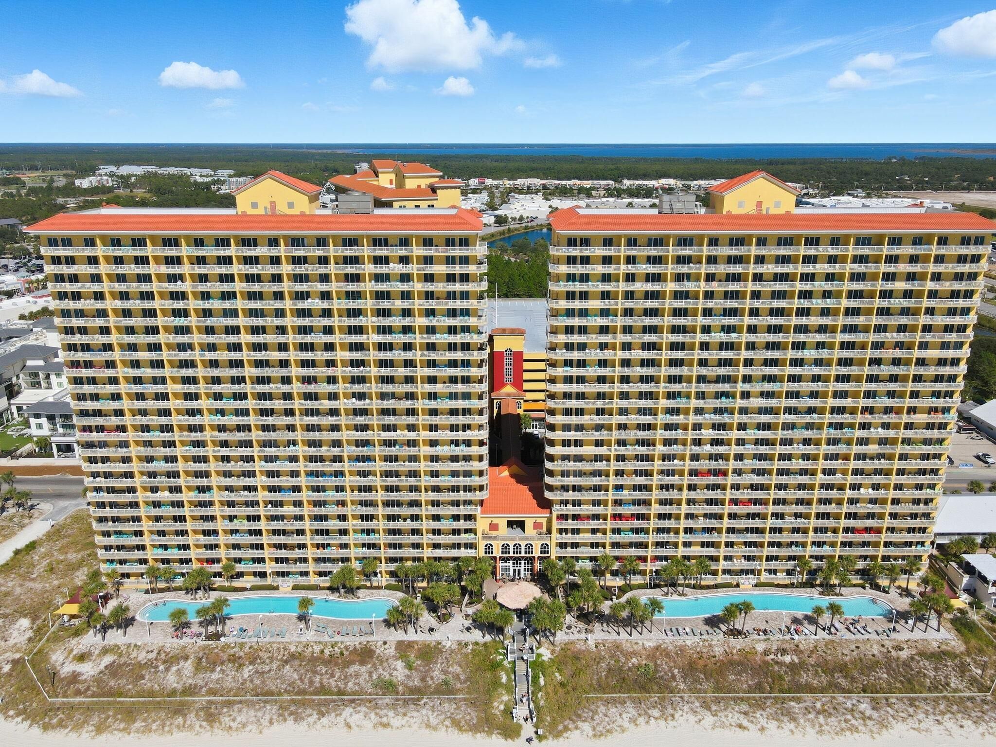 A large hotel with multiple floors, a central courtyard, and a pool area.