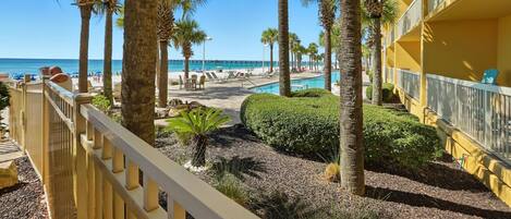A hotel with a pool area, palm trees, and a view of the beach.