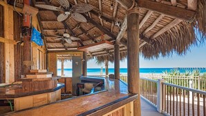 A wooden bar area with a thatched roof, overlooking a beach. - Calypso 1-203 East (Panama City Beach)