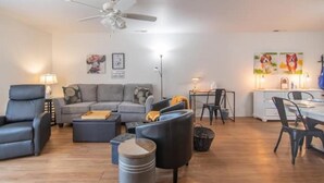 En moderne stue med en grå sofa, sorte lænestole, et sofabord og et spiseområde med bord og stole.