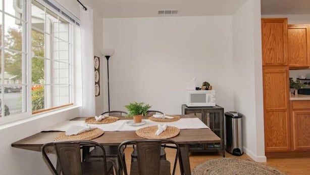 Un comedor con una mesa de madera, sillas y una planta en maceta.
