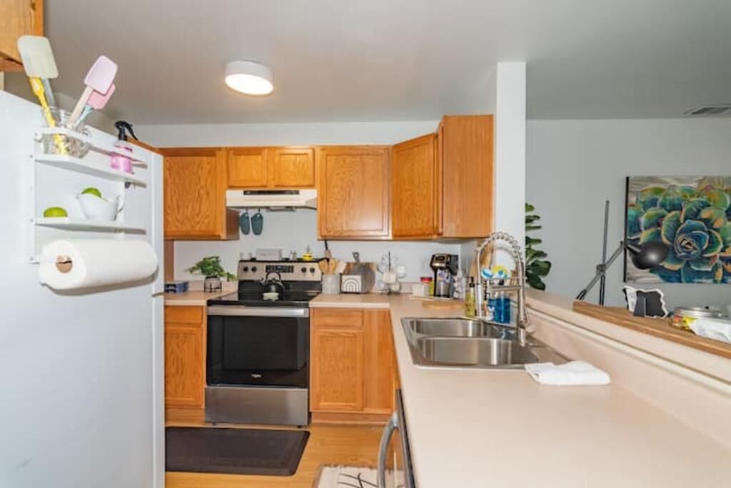A compact kitchen with wooden cabinets, a stainless steel sink, and a built-in oven.
