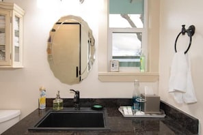 Une salle de bain avec un lavabo noir, un miroir, une fenêtre et un porte-serviettes.