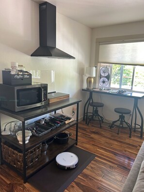 A kitchen with a microwave, coffee bar, and a robotic vacuum cleaner. - Cozy European Cottage 2 bd + 1 bath (ADU Ashland)
