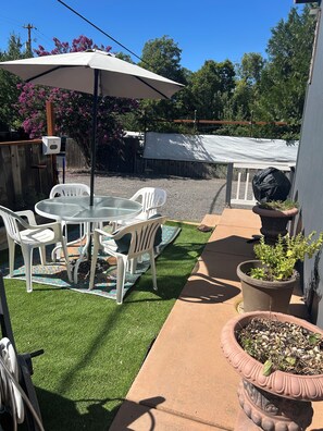 Une terrasse avec une table et des chaises, un parasol blanc et des plantes en pot.
