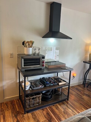A kitchen with a built-in oven, a range hood, and a wooden floor. - Cozy European Cottage 2 bd + 1 bath (ADU Ashland)