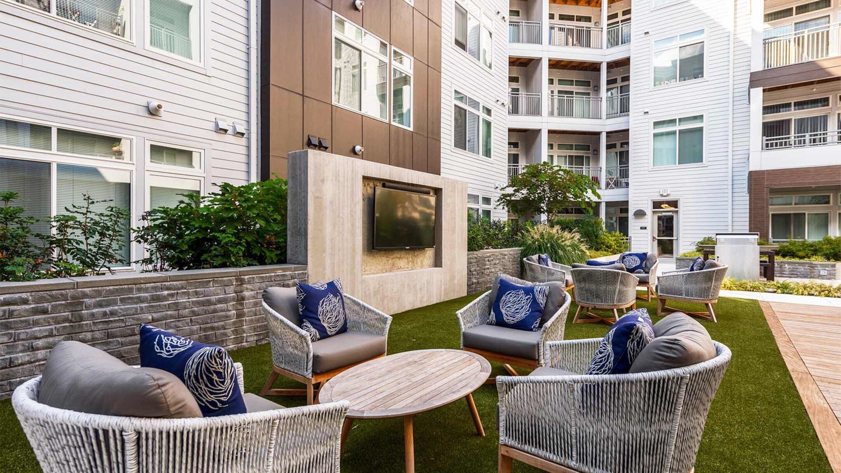 A courtyard with outdoor seating, a flat-screen TV, and a brick wall.