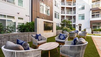 A courtyard with outdoor seating, a flat-screen TV, and a brick wall.