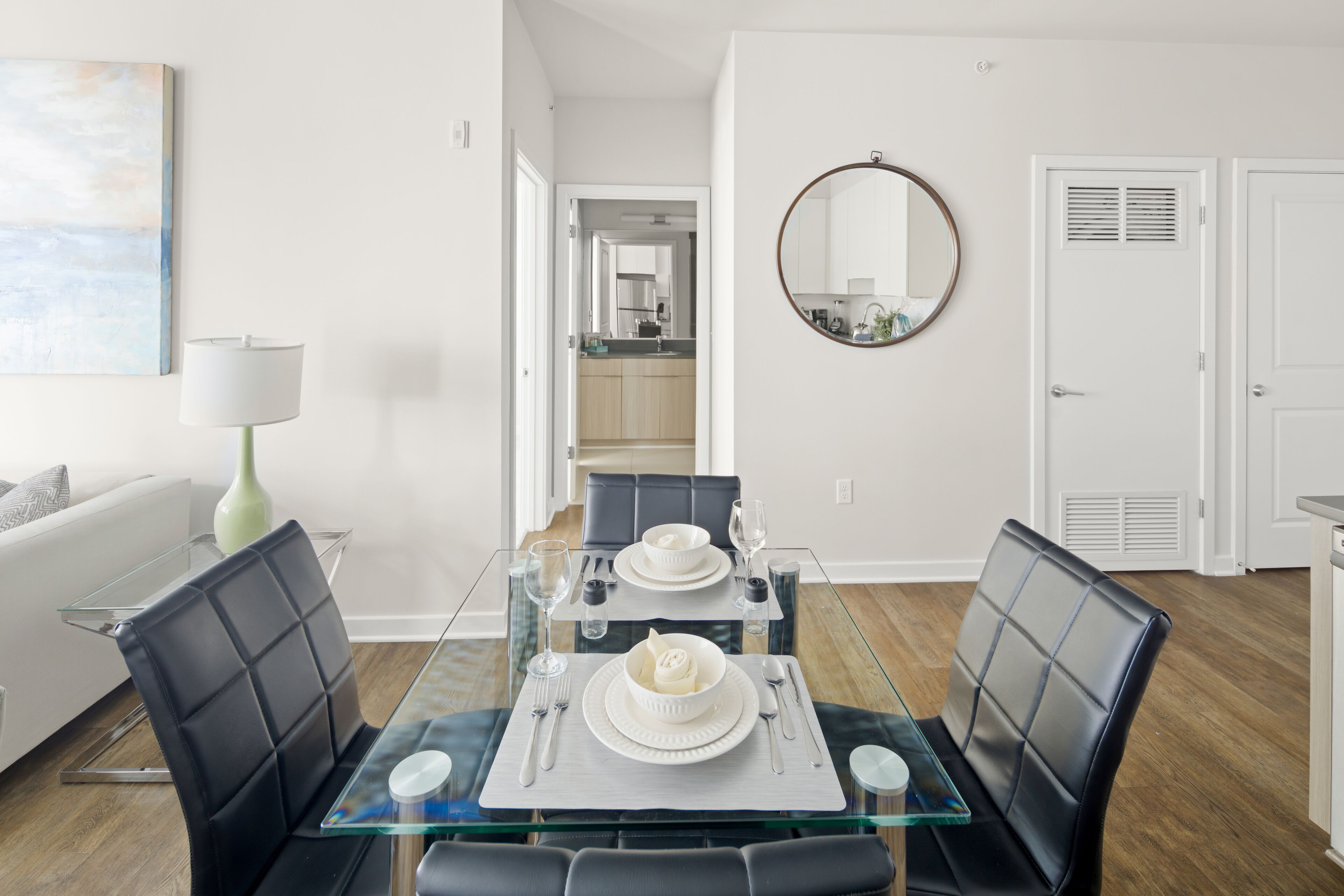 A modern dining area with a glass table, black cushioned chairs, and a white dining set.