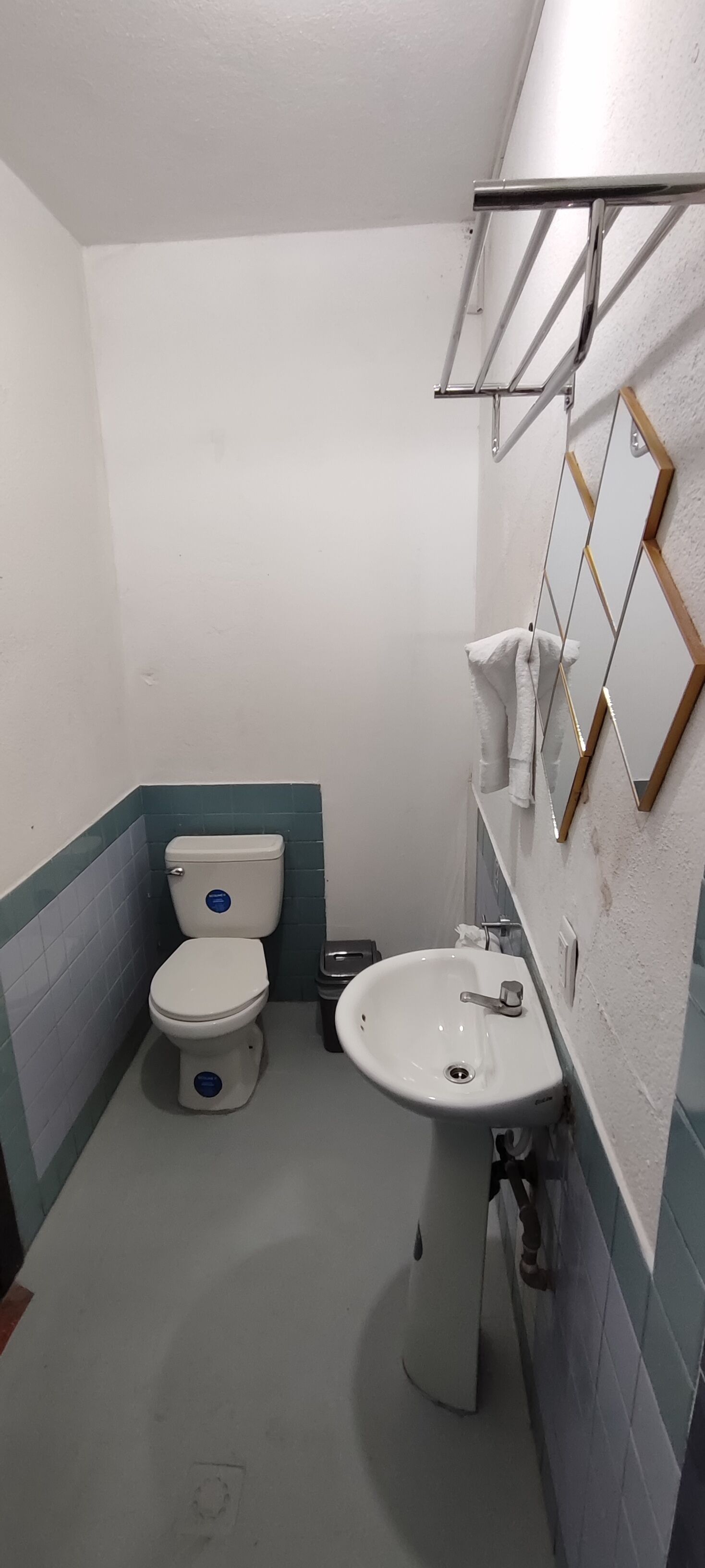 Un baño pequeño con inodoro, lavabo y espejo en la pared.