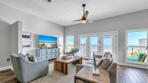 A spacious living room with a large TV, comfortable seating, a wooden coffee table, and a ceiling fan. - Beachside West 13 (Panama City Beach)