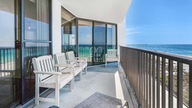 A balcony with white chairs, a table, and a view of the ocean. - Aquavista 404e (Panama City Beach)